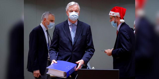 A colleague wears a Christmas hat while the chief EU negotiator, Michel Barnier, in the center, holds a file of a trade agreement for Brexit during a special meeting of Coreper, at the European Council building in Brussels, on December 25 (AP)