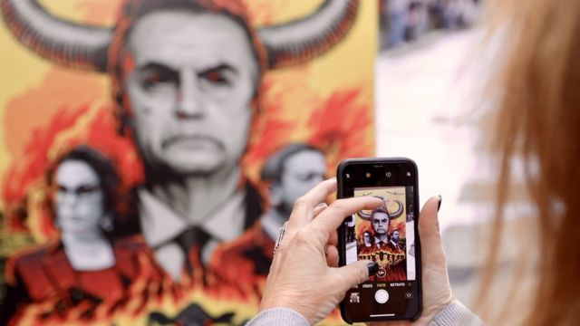 Um manifestante tira uma foto do presidente Bolsonaro.