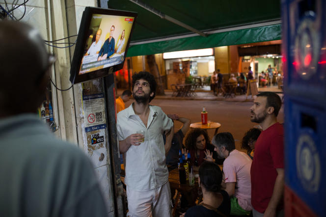 Brasileiros se reúnem em torno de uma fita de televisão transmitindo um vídeo de Jair Bolsonaro postado online, em um bar da Lapa, no Rio de Janeiro (Brasil), em outubro de 2018.