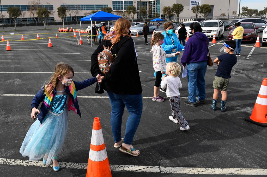 Pessoas com filhos se inscrevem para receber testes rápidos de Covid-19 no local de testes do Departamento de Saúde Pública de Long Beach em 10 de janeiro de 2022.