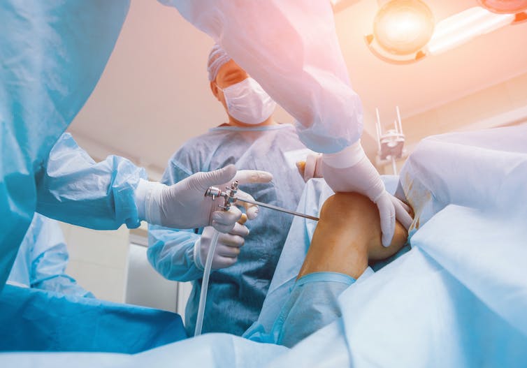 O cirurgião exercita o joelho na sala de cirurgia