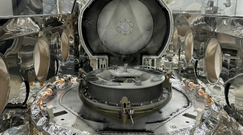A tampa da bandeja de retorno de amostras OSIRIS-REx está aberta, revelando um confuso anel de poeira fora da câmara principal de coleta de amostras.