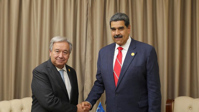 Nicolas Maduro e Antonio Guterres tiram uma foto enquanto apertam as mãos.