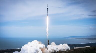 a black-and-white spacex falcon 9 rocket launches into a blue sky.