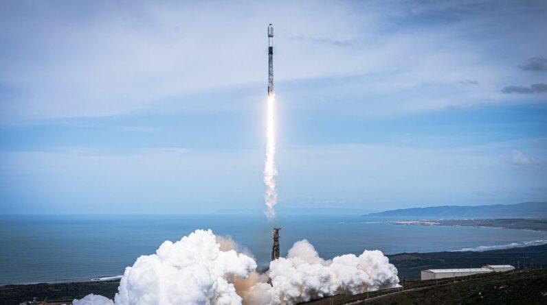 a black-and-white spacex falcon 9 rocket launches into a blue sky.