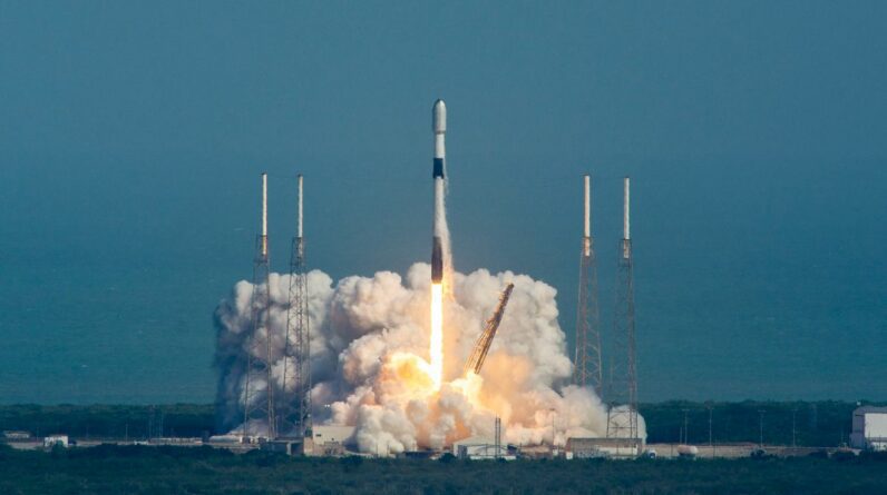 a black and white spacex falcon 9 rocket launches into a blue sky.