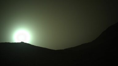the sun rises through a red, dusty haze on mars
