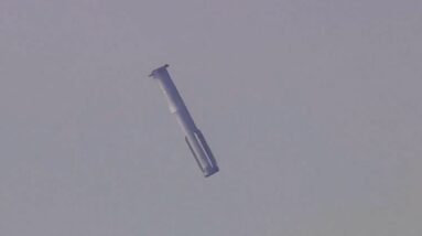 a silver-gray rocket is seen in a gray sky