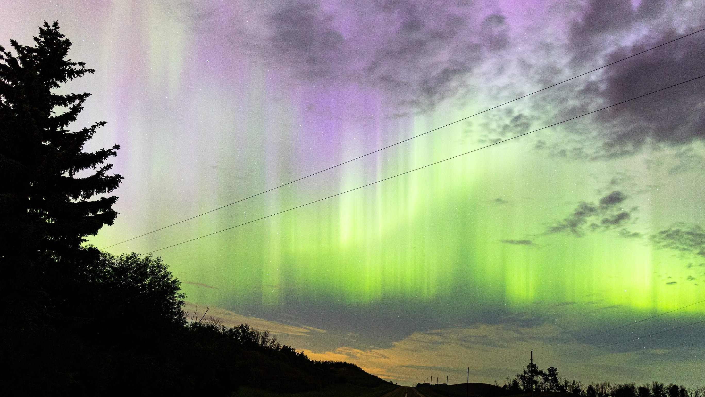 As luzes do norte aparecem como uma faixa verde vibrante de luz no céu.