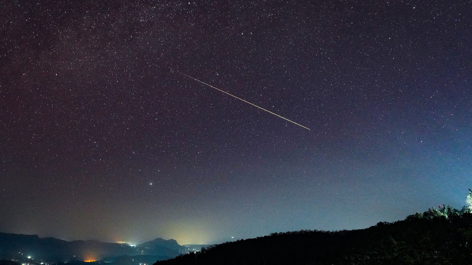 Uma linha de luz cruza o céu noturno